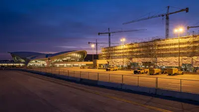 Editorial image: Airport terminal expansion construction at dusk - Dulles' $20B Expansion Sets Up Phased Bid Calendar for Subs