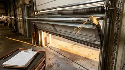 Editorial image: technician inspecting overhead door hardware - Commercial Door Safety Inspection Habits Help Prevent Struck-By, Crush Injuries