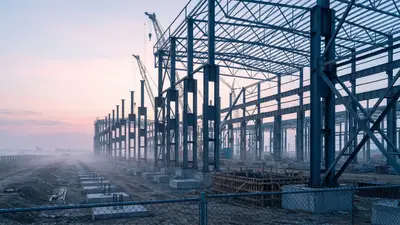 Editorial image: Steel skeleton rising at dawn - PowerCo's $7B St. Thomas Gigafactory Enters Vertical Build, MEP Packages Still Open