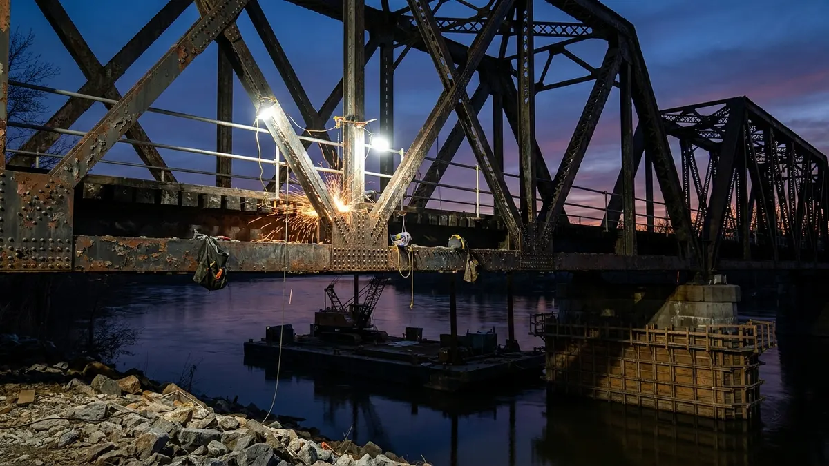 Editorial image: Historic truss bridge steel repair at dusk - Amtrak Launches $242M Dock Bridge Rehab on Northeast Corridor
